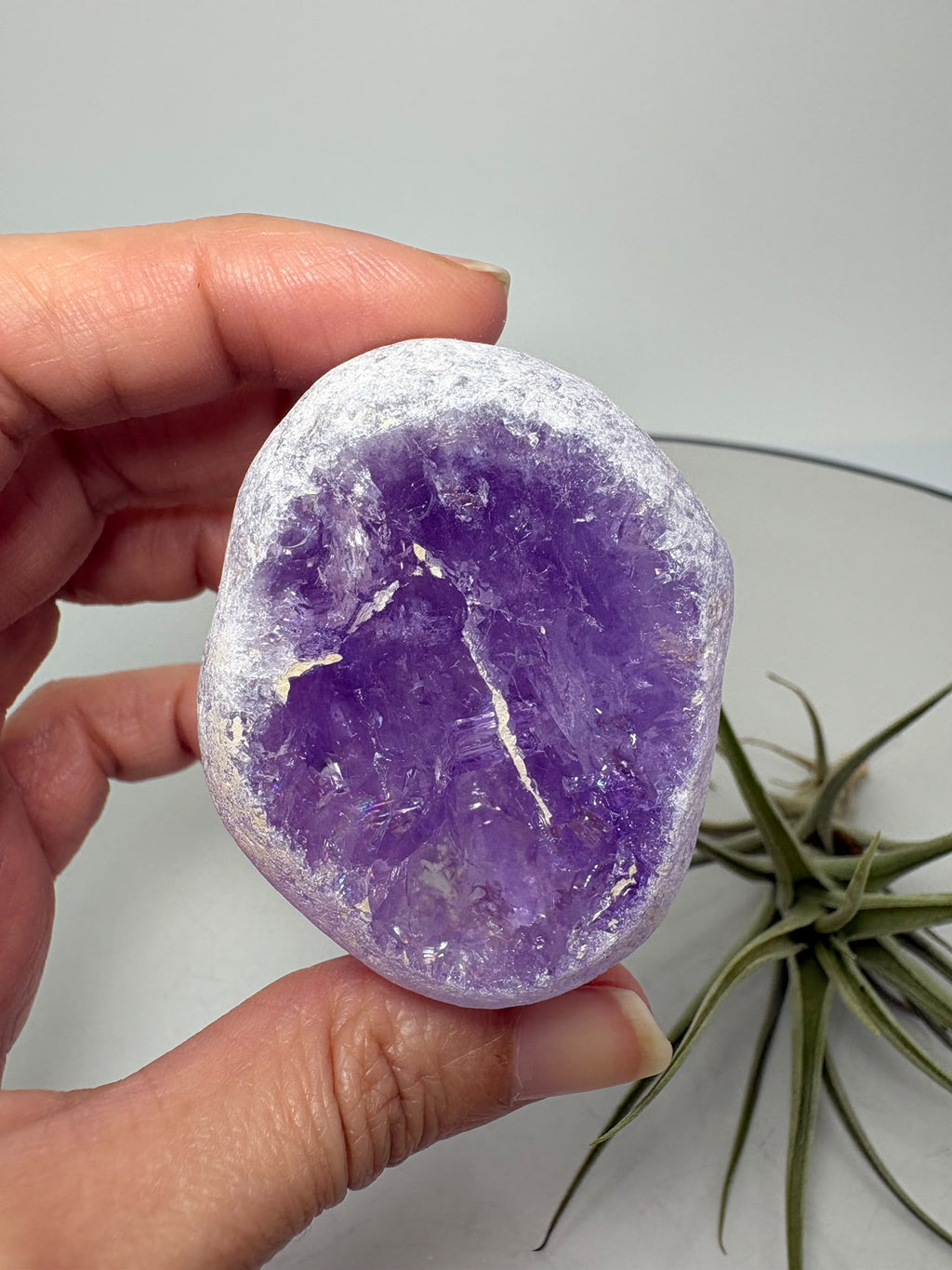 Amatista visión ahumada de gran calidad, con tonos violetas, zonas transparentes y pequeños destellos arcoíris. Descúbrela en La Hada de las Piedras.