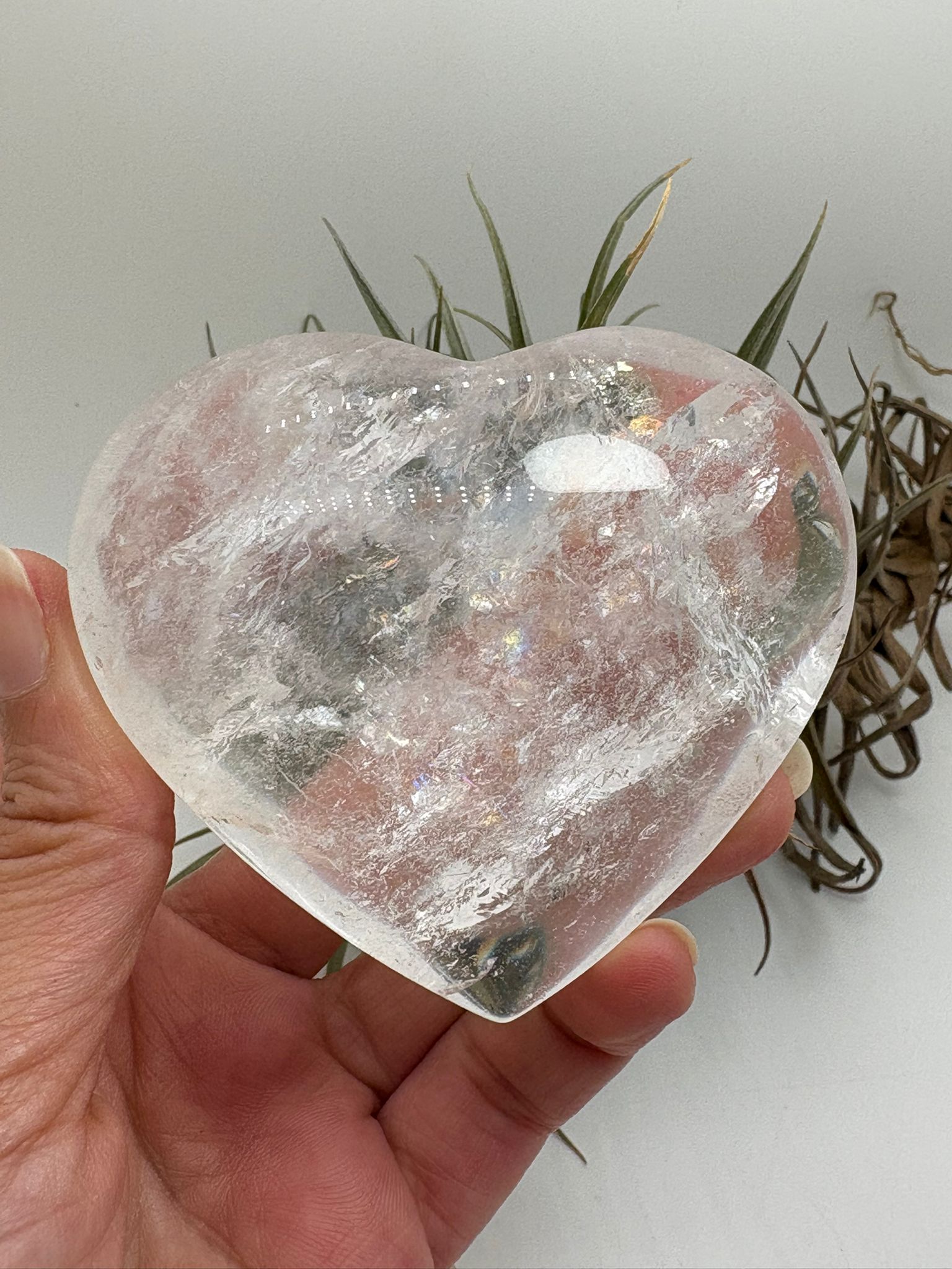 Corazón de cuarzo cristal transparente con preciosos reflejos arcoíris naturales en su interior. Una pieza pulida llena de luz y energía, ideal para decorar, meditar o trabajar la claridad mental y la armonía energética.
