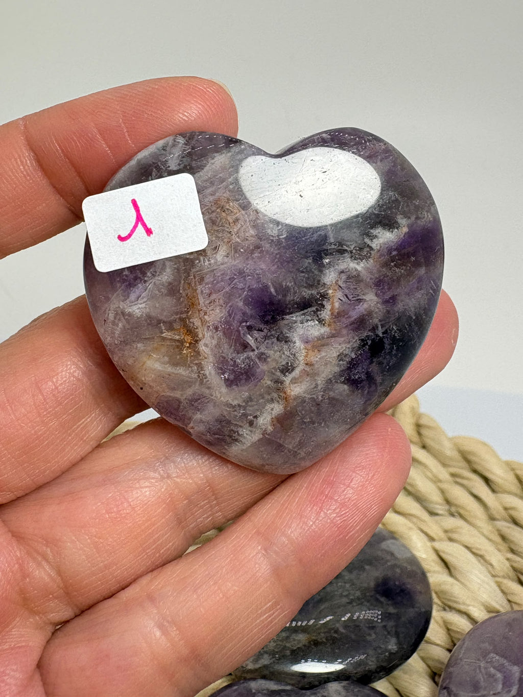 Corazón de amatista plano, con superficie pulida, vetas claras y tonos violetas