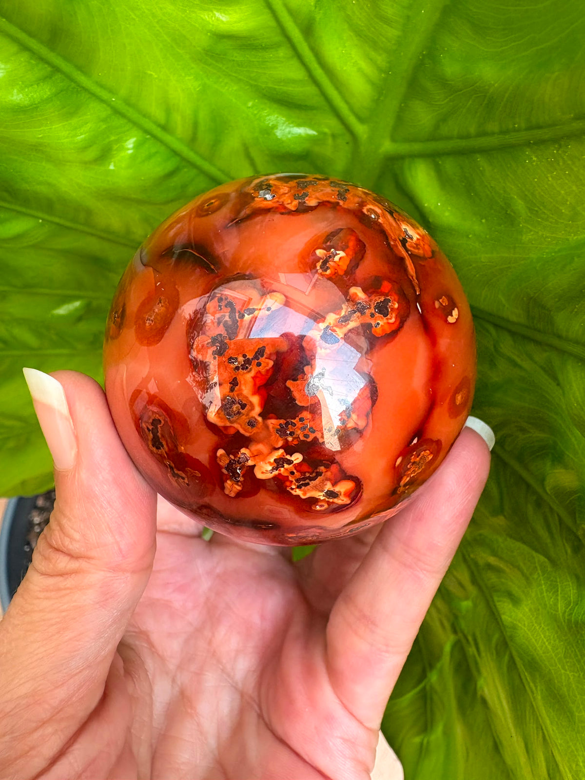 esfera de cornalina natural de tonos naranjas y rojizos, asociada con la vitalidad, la creatividad, la motivación y la confianza.