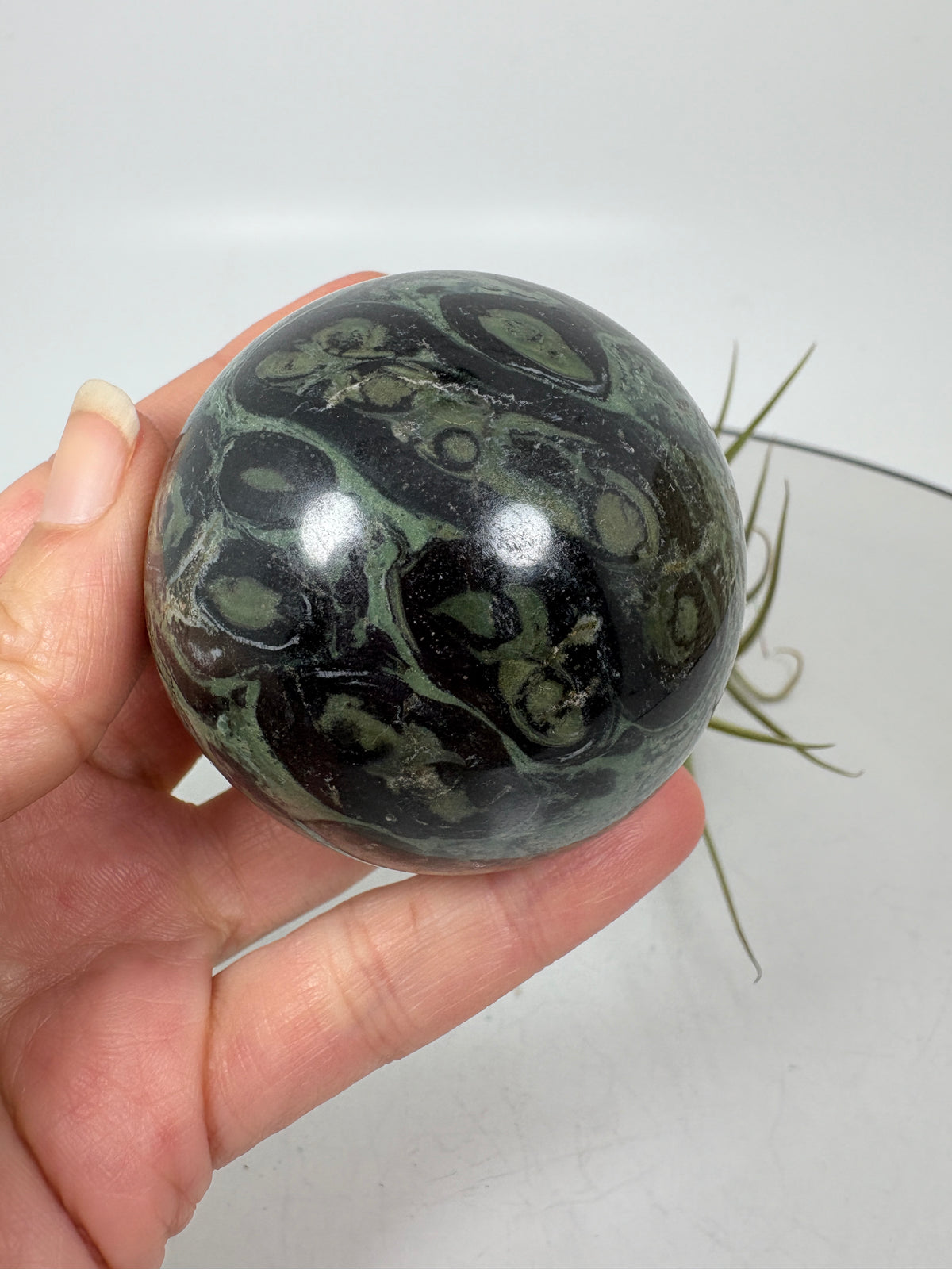 Esfera de jaspe kambaba de Madagascar de 5,2 cm y 206 g. Una pieza de tonos verdes y dibujos únicos, asociada con la calma y el equilibrio.
