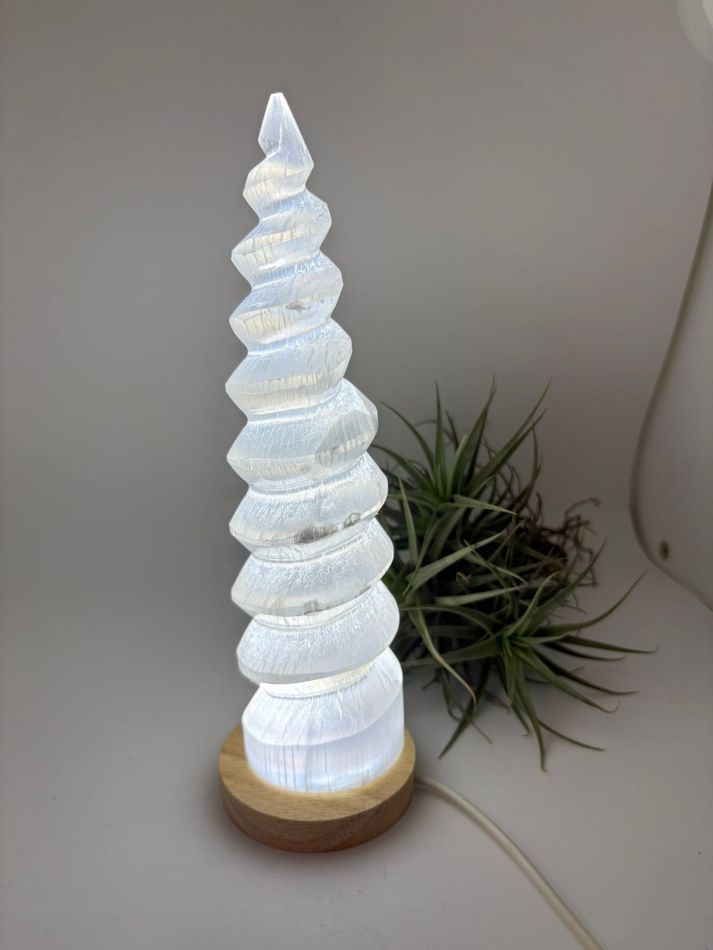 Lámpara de selenita natural en forma de torre espiral con base LED. Altura 26 cm, ideal para decoración y ambiente relajante.