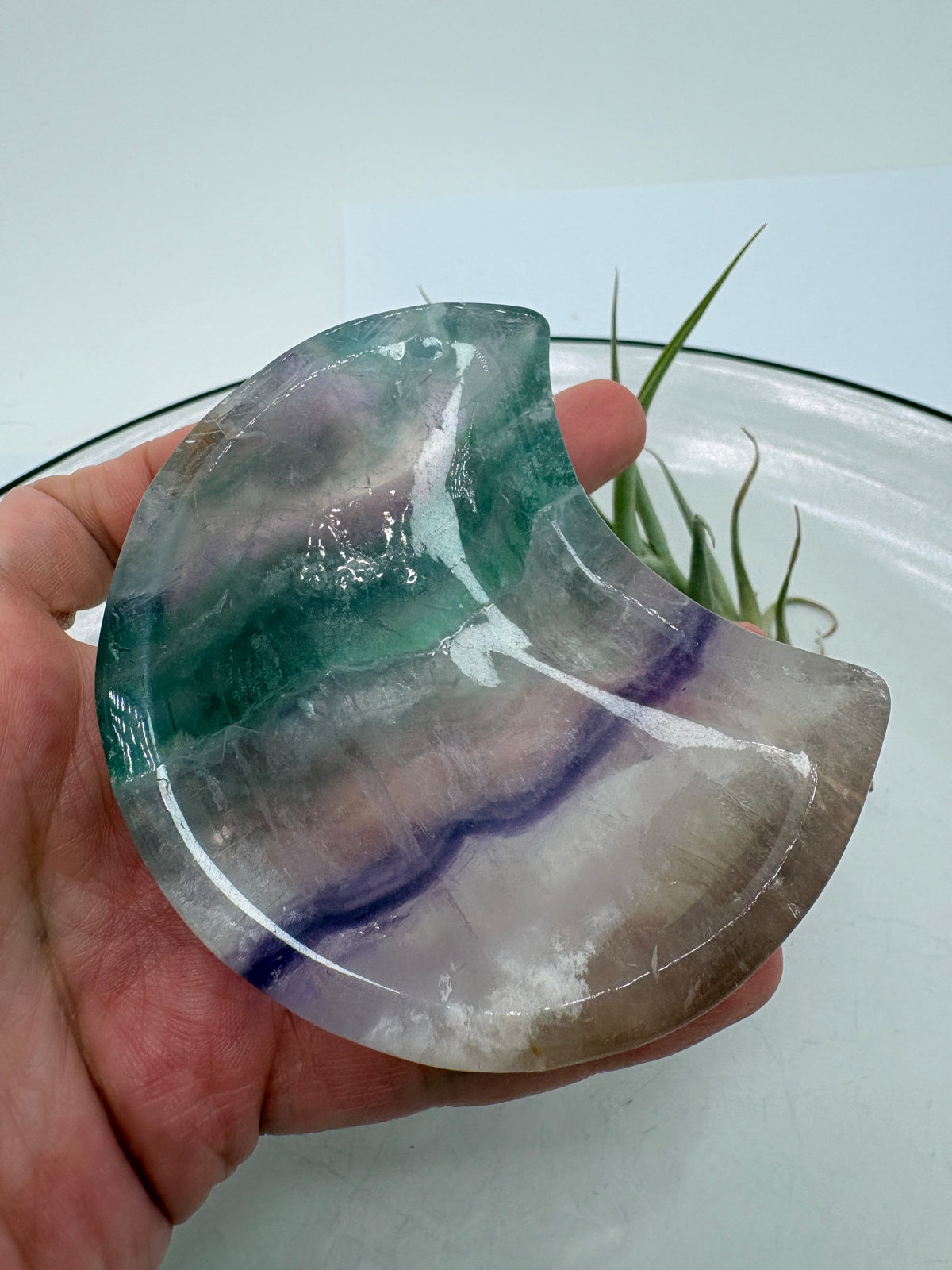 Una pequeña bandeja de fluorita arcoíris tallada en forma de luna, perfecta para colocar tus anillos, pendientes o algún pequeño mineral. Una pieza bonita y especial para tu mesita de noche, tocador o rincón de meditación.
