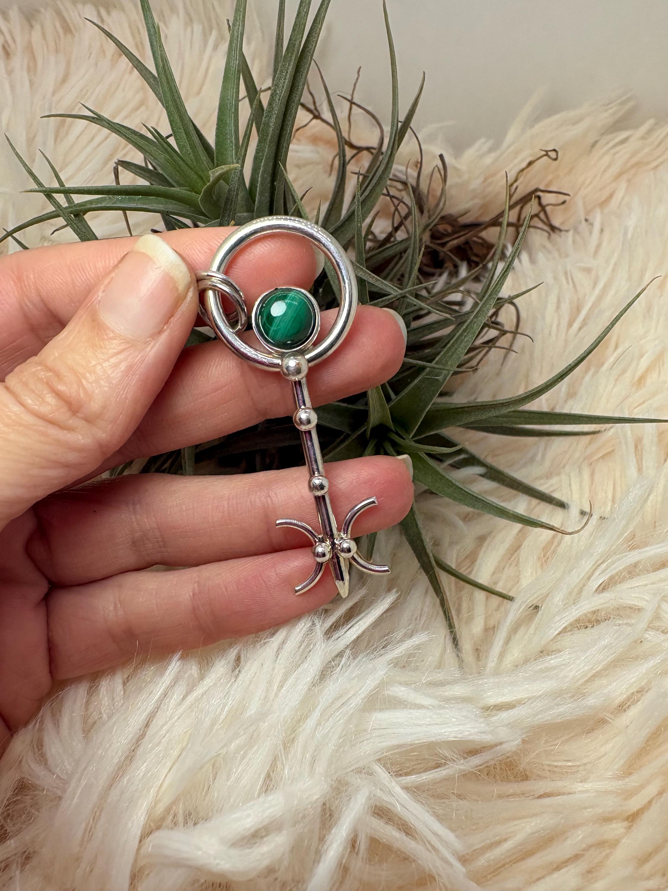 Colgante llave de malaquita en plata de ley artesanal. Joya con significado que abre caminos y favorece la transformación personal.