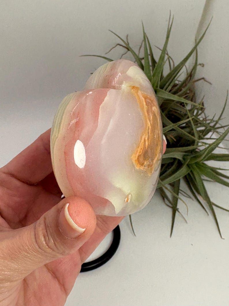 Corazón de ónix rosado con energía de calma, amor propio y equilibrio emocional. Pieza única ideal para armonizar espacios y acompañar procesos interiores.