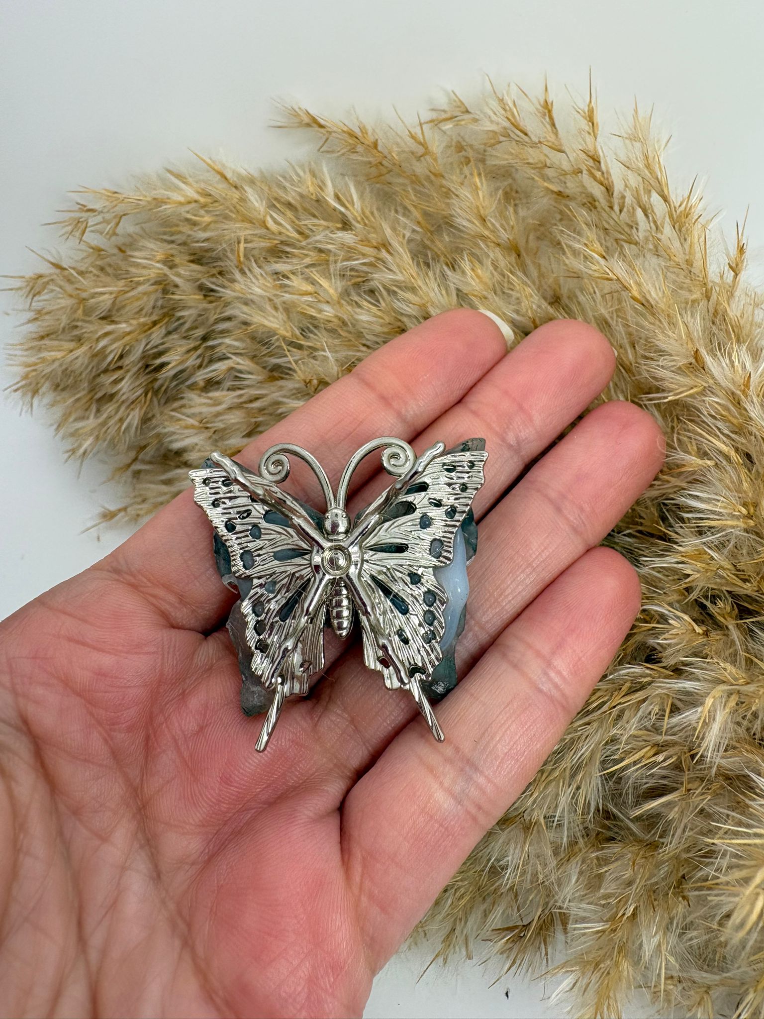 Mariposa de ágata musgo natural tallada, con tonos verdes y dibujos únicos. Pieza decorativa ideal para colección o regalo.
