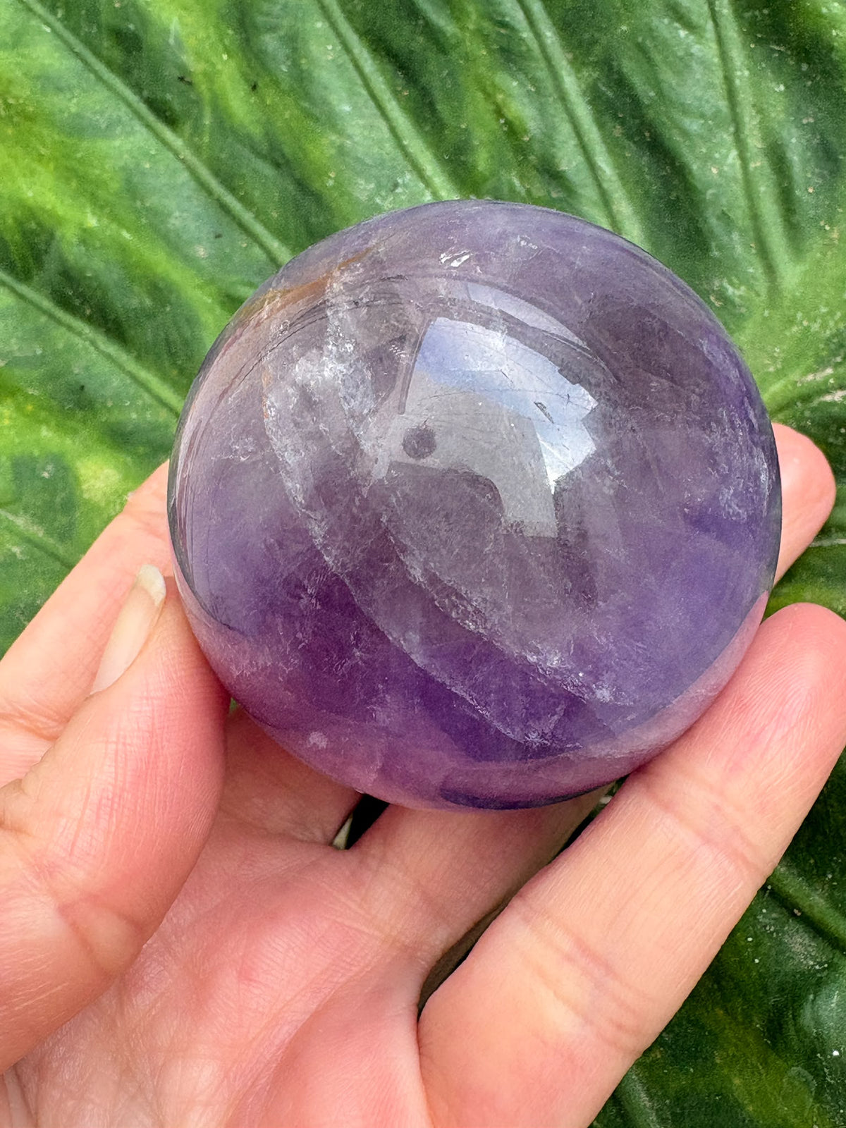 Esfera de amatista lila con zona ahumada y acabado pulido. Una pieza única para decorar o acompañar tu meditación en La Hada de las Piedras.