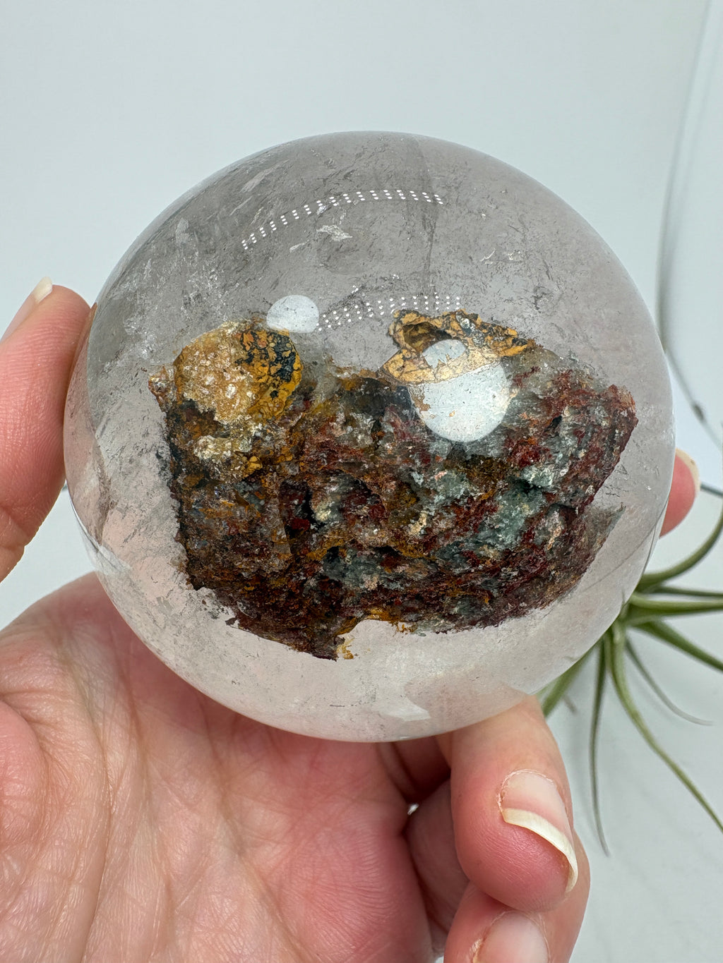 Impresionante esfera de cuarzo chamánico de gran tamaño, una pieza única llena de carácter y belleza natural.

Su interior presenta inclusiones, velos y fracturas naturales que crean espectaculares reflejos arcoíris al recibir la luz.