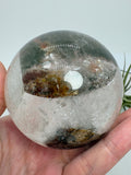 Impresionante esfera de cuarzo chamánico de gran tamaño, una pieza única llena de carácter y belleza natural.

Su interior presenta inclusiones, velos y fracturas naturales que crean espectaculares reflejos arcoíris al recibir la luz.