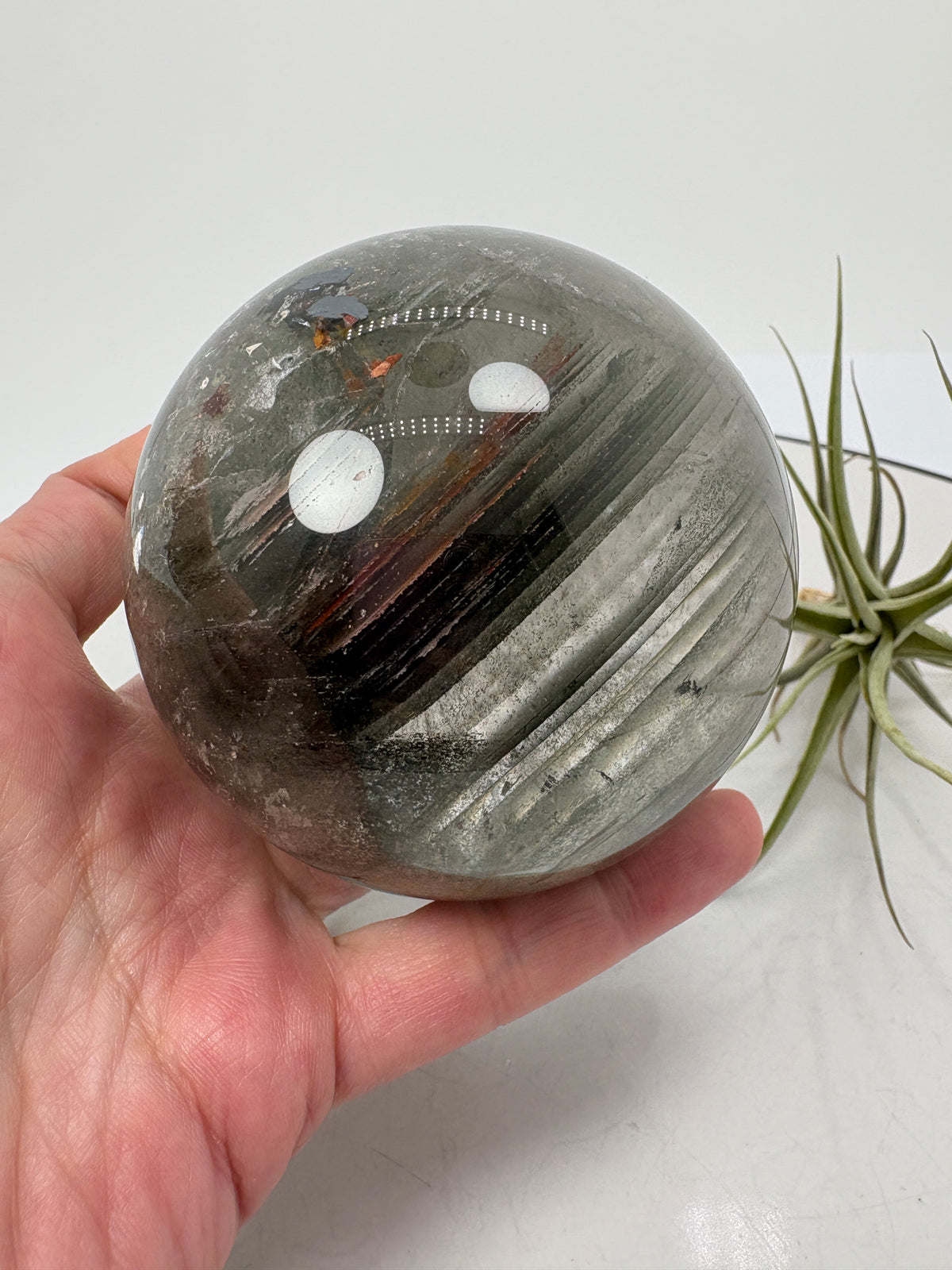 Impresionante esfera de cuarzo chamánico de gran tamaño, una pieza única llena de carácter y belleza natural.

Su interior presenta inclusiones, velos y fracturas naturales que crean espectaculares reflejos arcoíris al recibir la luz.