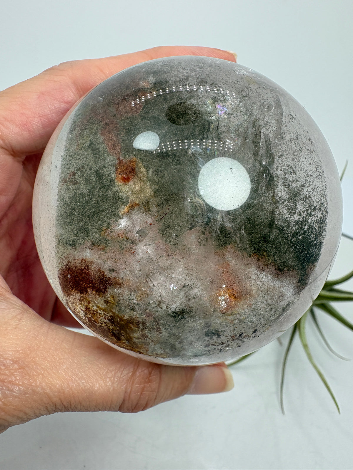 Impresionante esfera de cuarzo chamánico de gran tamaño, una pieza única llena de carácter y belleza natural.

Su interior presenta inclusiones, velos y fracturas naturales que crean espectaculares reflejos arcoíris al recibir la luz.