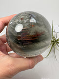Impresionante esfera de cuarzo chamánico de gran tamaño, una pieza única llena de carácter y belleza natural.

Su interior presenta inclusiones, velos y fracturas naturales que crean espectaculares reflejos arcoíris al recibir la luz.