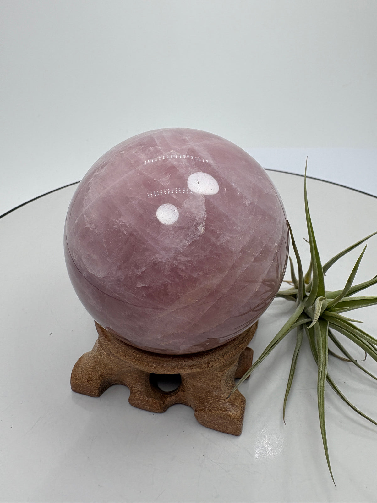 Una preciosa esfera de cuarzo rosa con zonas translúcidas y delicados velos blancos que recorren su interior. Su superficie pulida permite apreciar los distintos matices del mineral, creando una pieza llena de detalles para decorar un rincón especial o regalar con cariño.