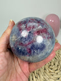 Esfera de piedra unicornio con lepidolita, turmalina rosa, cuarzo, cuarzo ahumado y mica. Una pieza única de preciosos tonos lilas y rosados.
