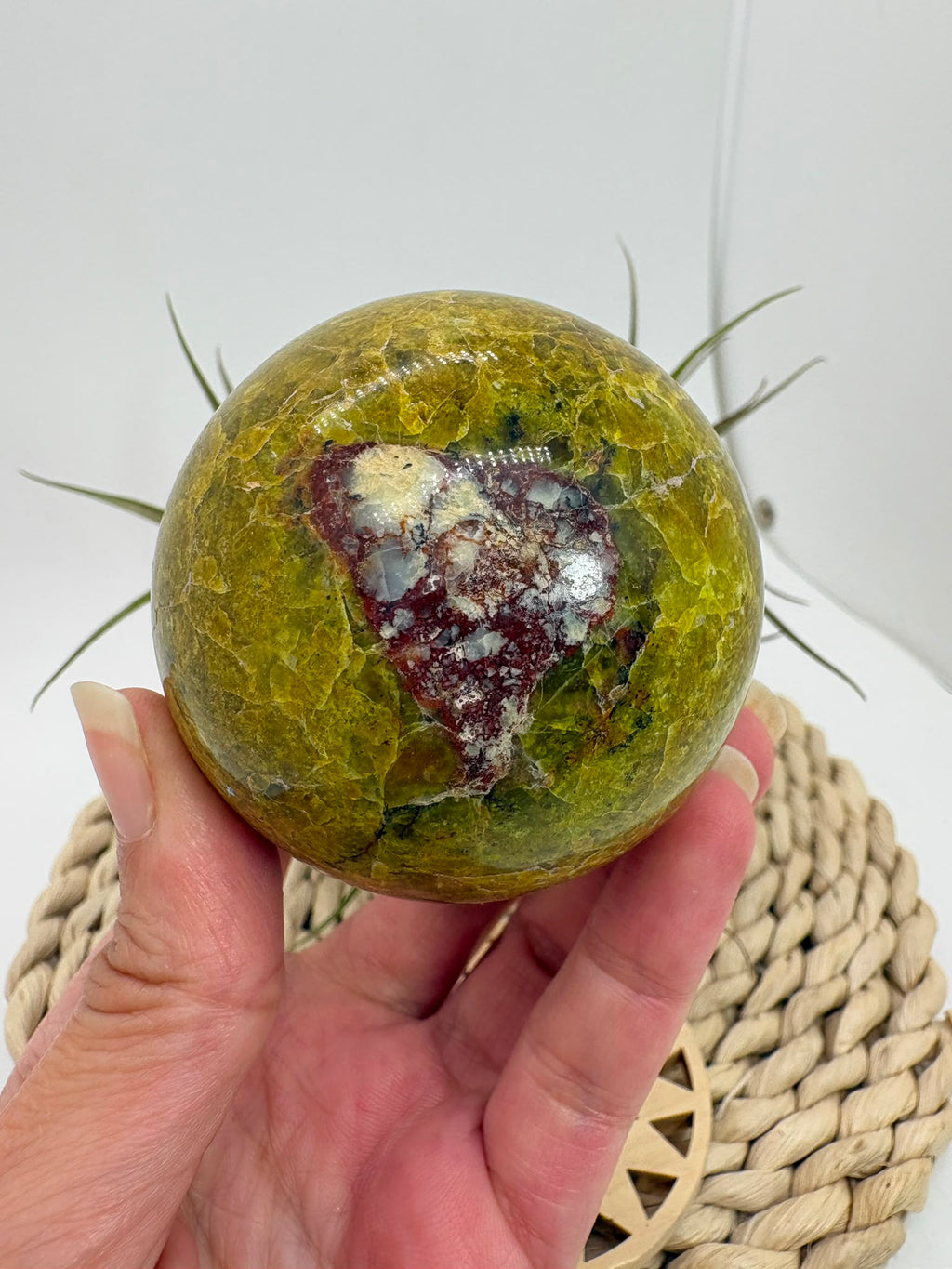 Preciosa esfera de ópalo verde procedente de Madagascar, caracterizada por sus tonalidades verdes, amarillentas y blancas, que forman dibujos naturales únicos en toda la superficie. Su pulido realza el color, el brillo y la riqueza de sus matices.