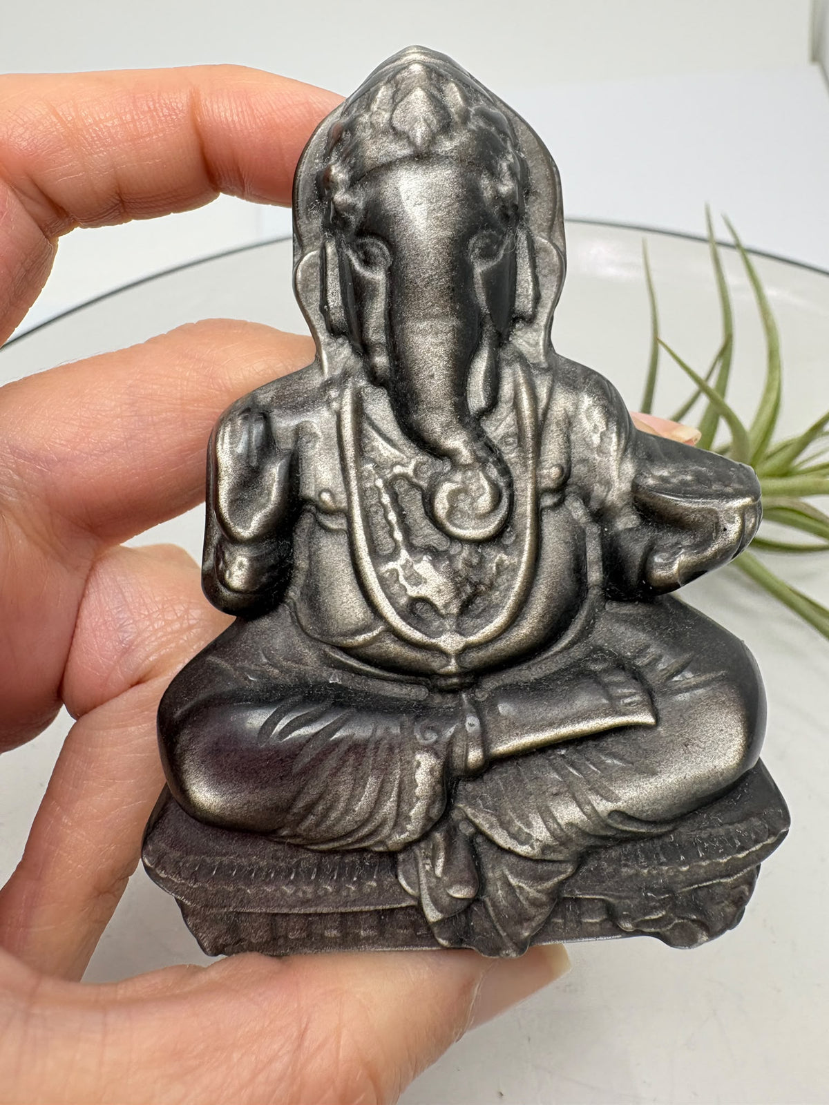 Descubre este Ganesha de obsidiana plateada tallado a mano de 7,7 cm. Una figura de bellos reflejos, ideal para decorar, meditar o regalar.