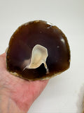 Media geoda de ágata natural semipulida de Brasil con cavidad central y bandas marrones translúcidas pieza única