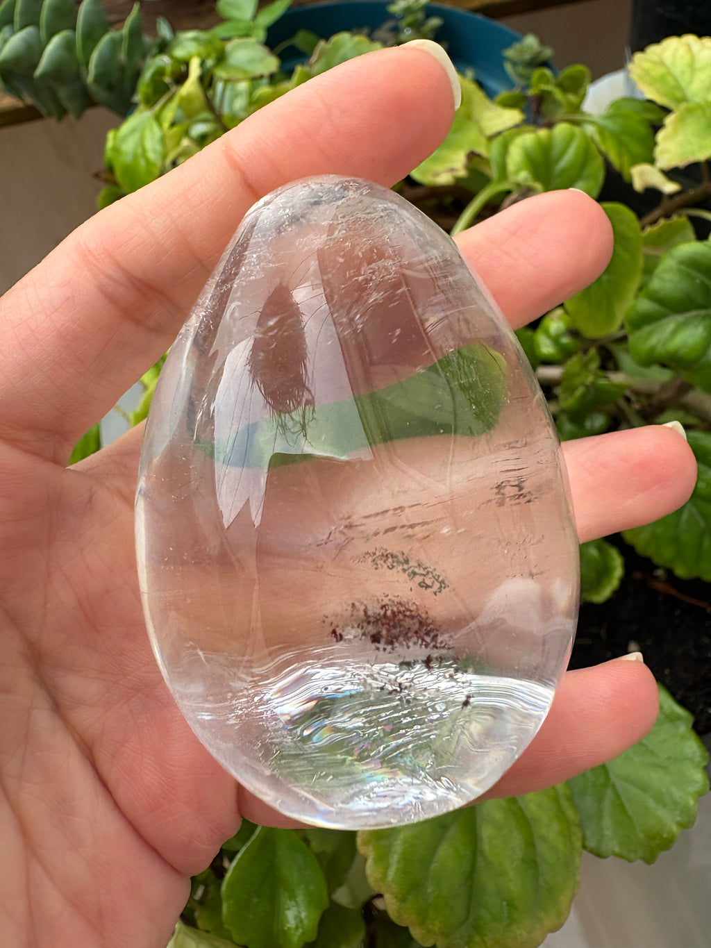 Huevo de cuarzo muy cristalino con inclusiones de lodolita en su interior. Su transparencia permite apreciar pequeños detalles en tonos rojizos y terrosos, como un diminuto paisaje suspendido dentro del cristal. Una pieza para observar de cerca y descubrir desde diferentes ángulos.