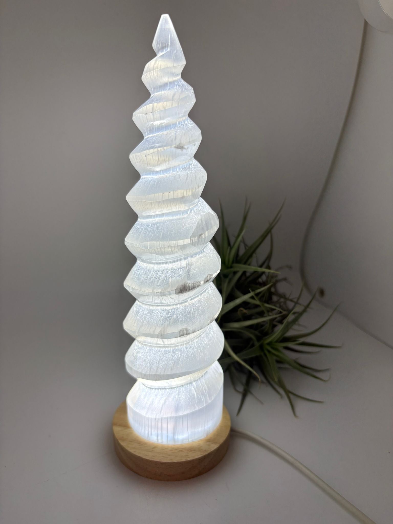 Lámpara de selenita natural en forma de torre espiral con base LED. Altura 26 cm, ideal para decoración y ambiente relajante.