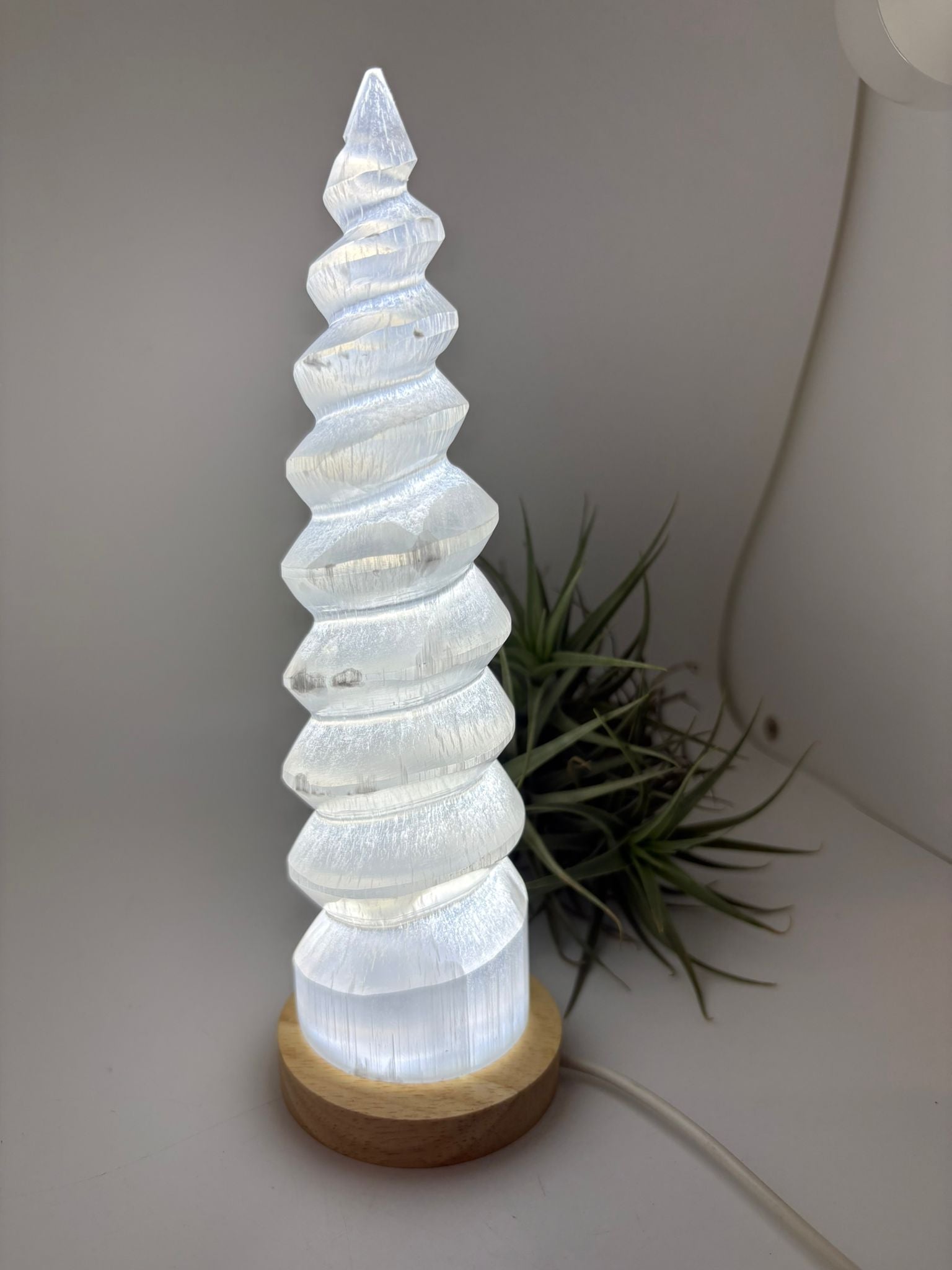 Lámpara de selenita natural en forma de torre espiral con base LED. Altura 26 cm, ideal para decoración y ambiente relajante.