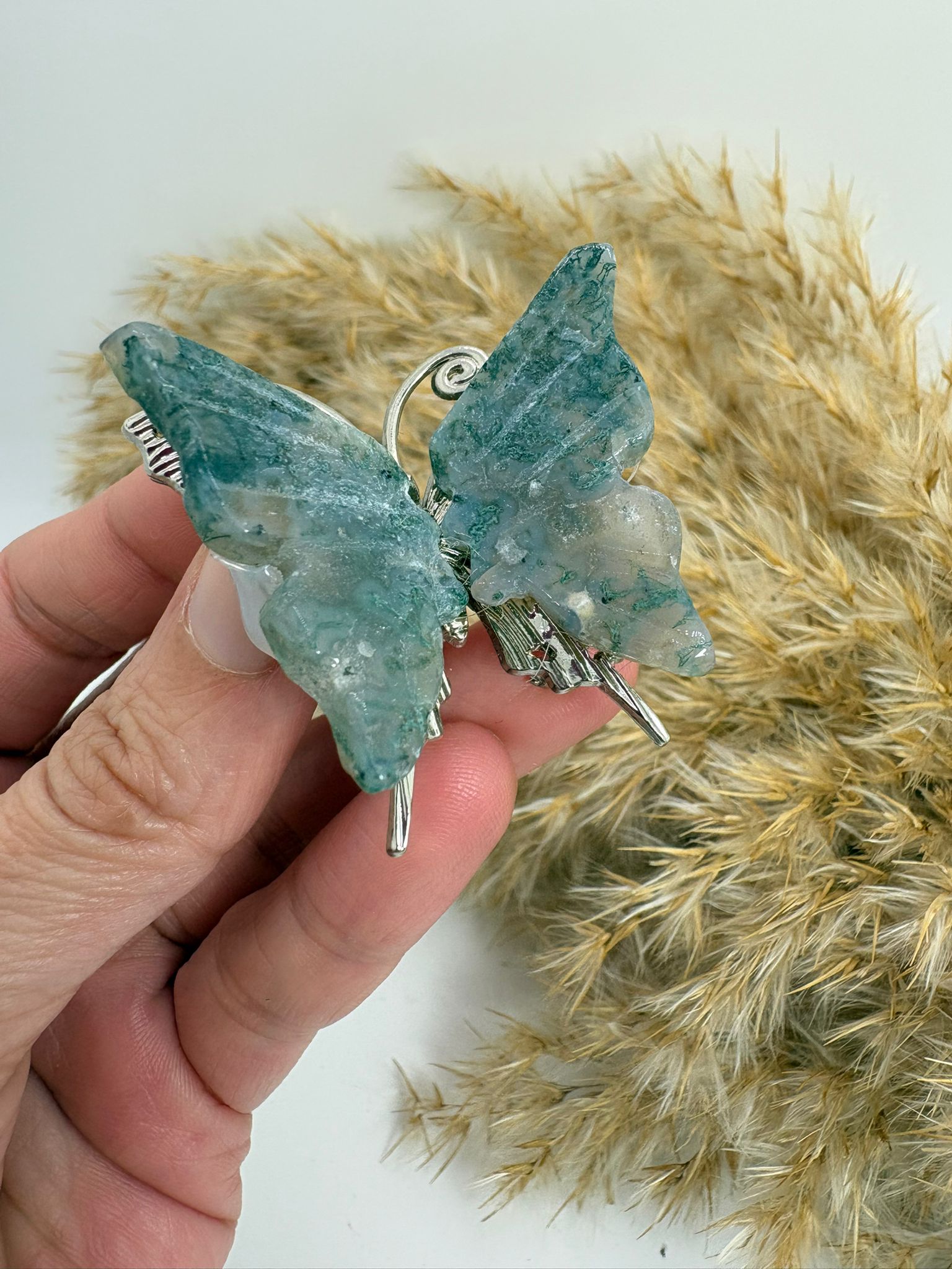 Mariposa de ágata musgo natural tallada, con tonos verdes y dibujos únicos. Pieza decorativa ideal para colección o regalo.