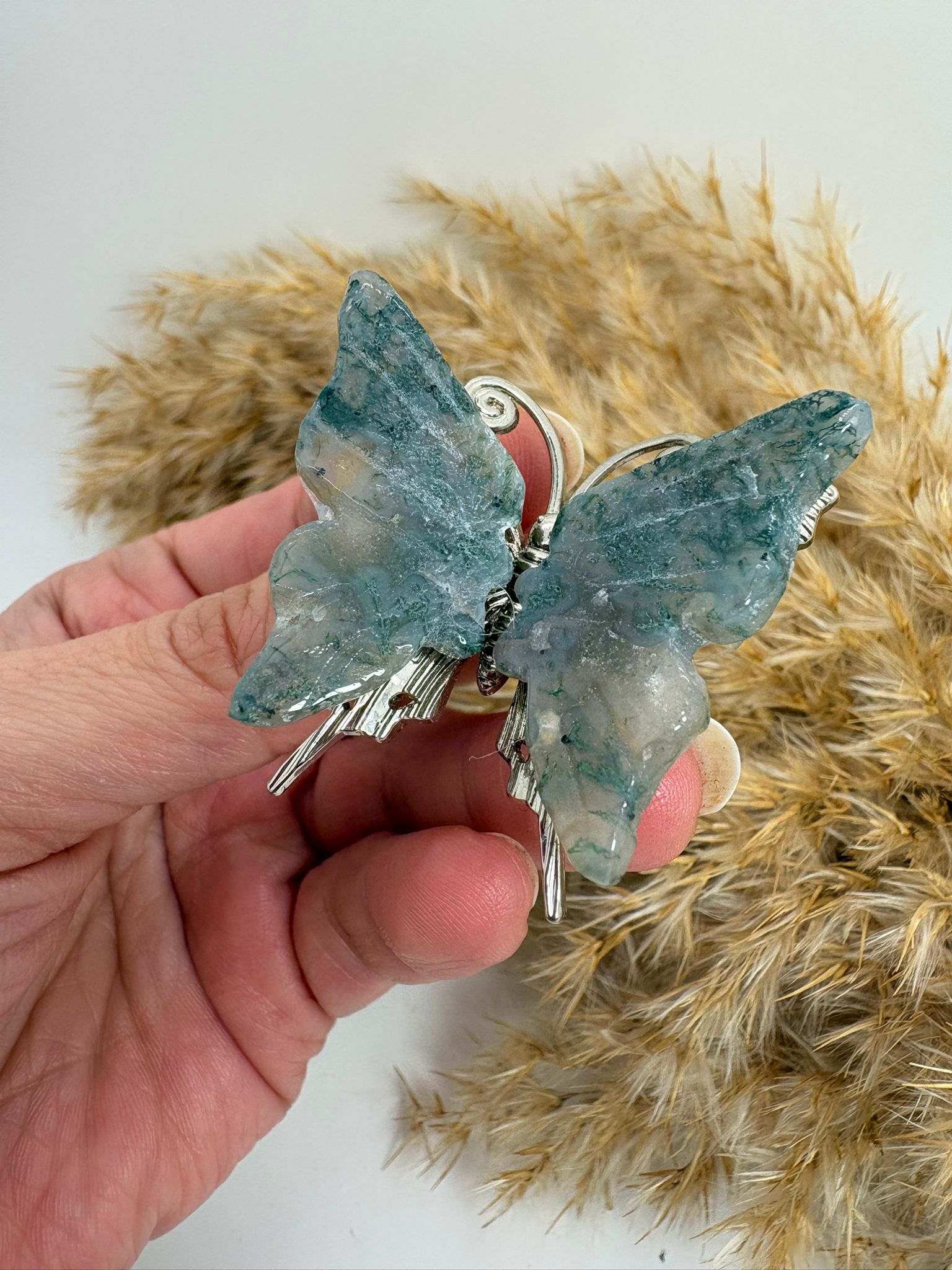 Mariposa de ágata musgo natural tallada, con tonos verdes y dibujos únicos. Pieza decorativa ideal para colección o regalo.