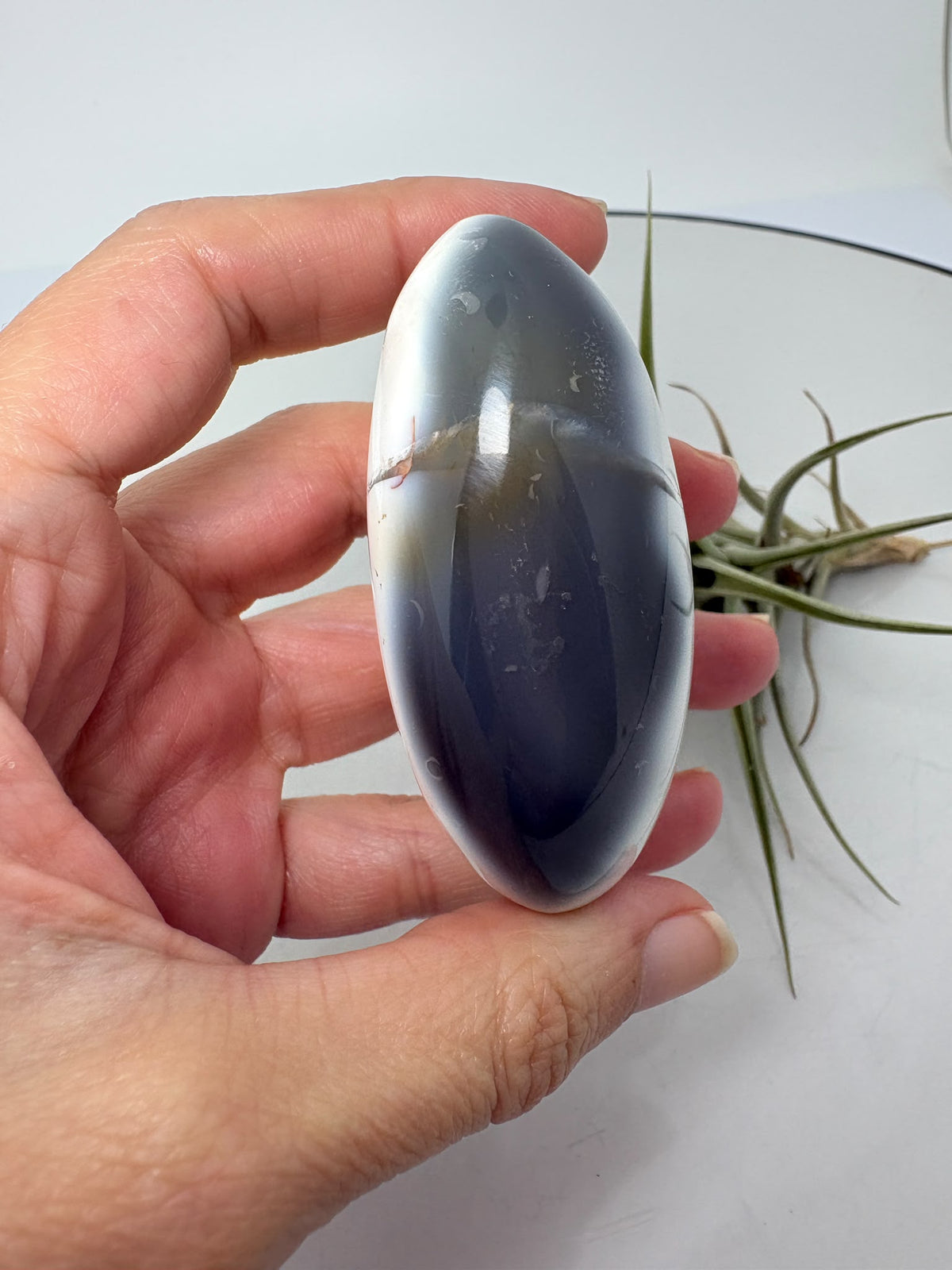 Palmstone de ágata orca en tonos gris azulados y blanco, con acabado pulido. Una pieza única para tu colección o tus momentos de meditación