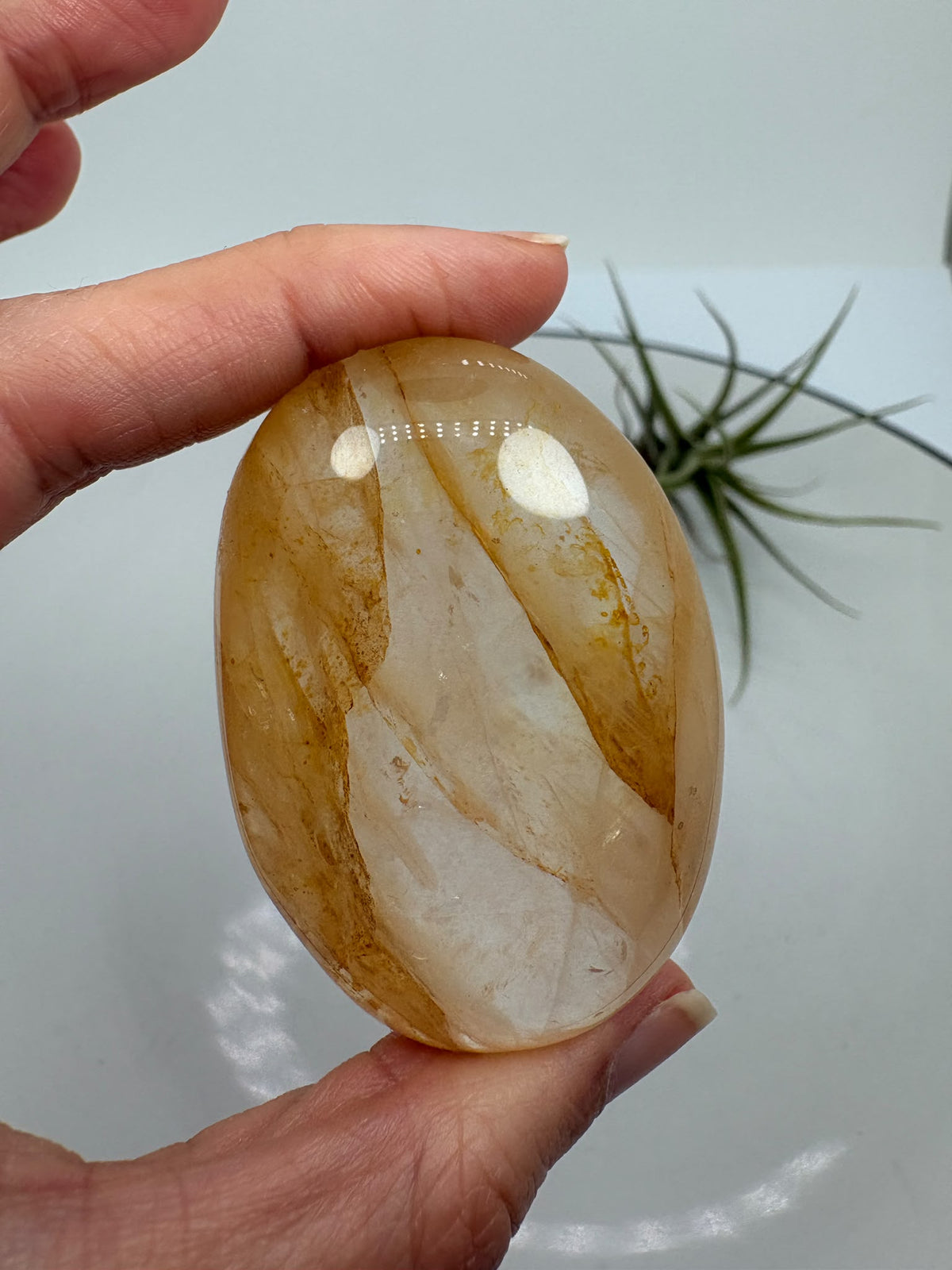 Palmstone de cuarzo hematoide de gran calidad y transparencia. Su interior presenta preciosas inclusiones en tonos anaranjados, rojizos y dorados, acompañadas de dibujos oscuros que forman un paisaje único dentro del cuarzo.