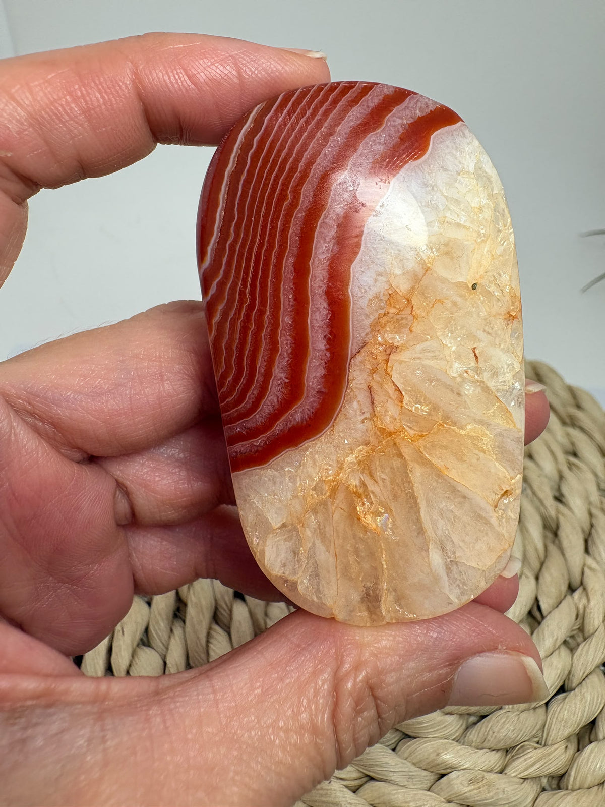 Descubre esta palmstone de ágata cornalina pulida, con bandas rojizas y tonos crema. Recibe la pieza fotografiada de La Hada de las Piedras.