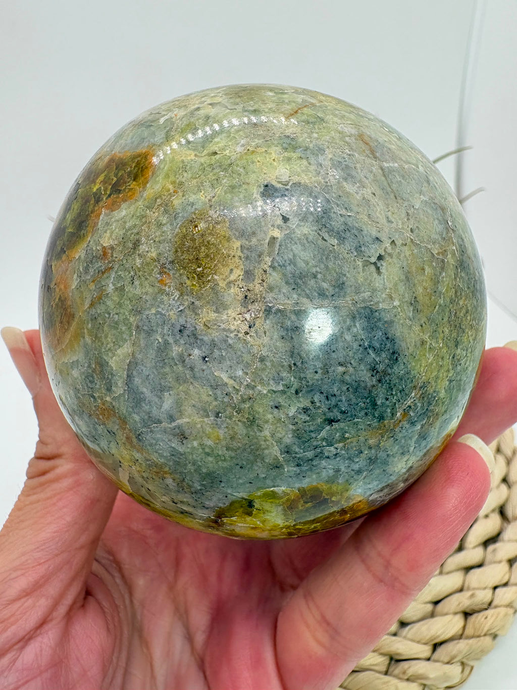 Preciosa esfera de ópalo verde procedente de Madagascar, caracterizada por sus tonalidades verdes, amarillentas y blancas, que forman dibujos naturales únicos en toda la superficie. Su pulido realza el color, el brillo y la riqueza de sus matices.