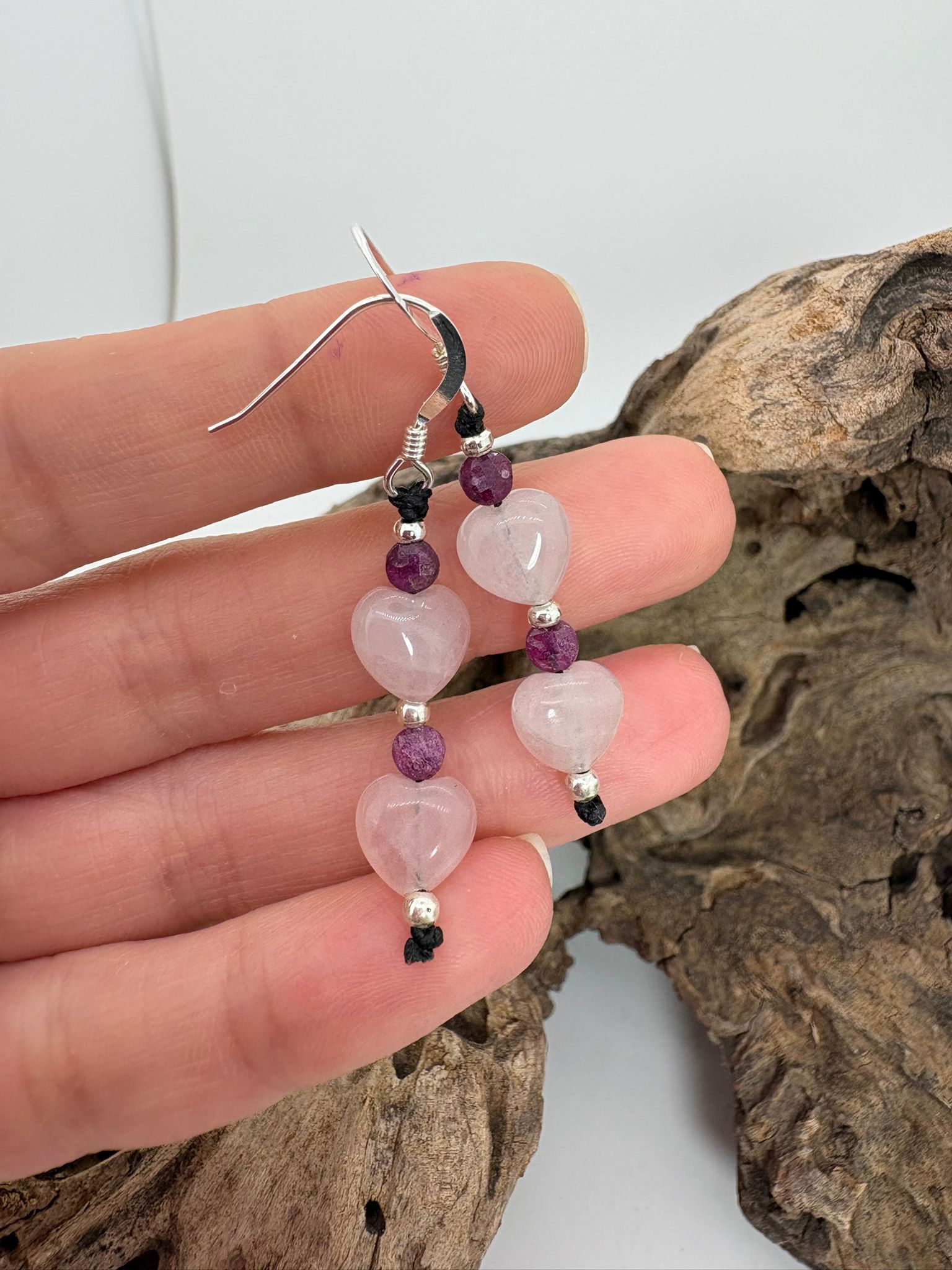 Pendientes artesanales de macramé con corazones de cuarzo rosa y rubí natural. Elaborados con plata de ley 925 e hilo de algodón encerado. Diseño romántico y hecho a mano.