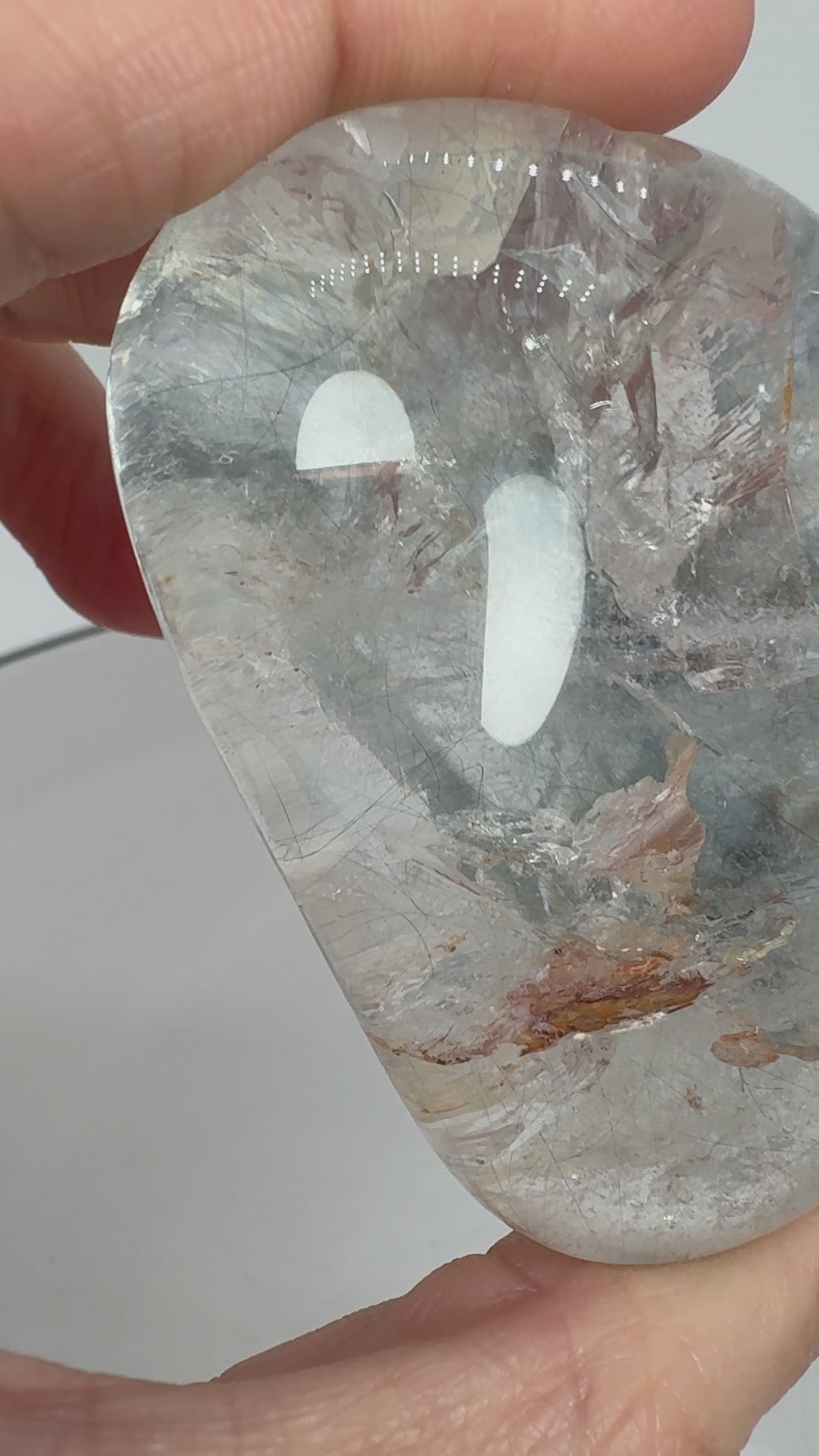 Un pequeño universo natural en el interior del cuarzo. Este palmstone contiene finas agujas de rutilo e inclusiones de aspecto plateado, que crean un paisaje lleno de detalles entre transparencias y delicados matices cálidos.