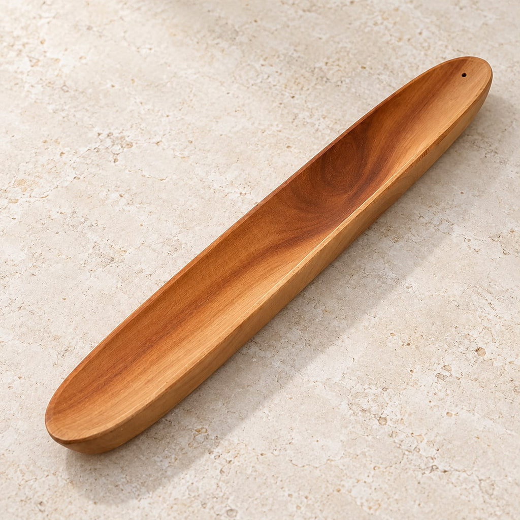 Portaincienso de madera en forma de barca, con vetas naturales y diseño alargado para recoger las cenizas. Medidas: 28,3 × 4 × 1,5 cm.
